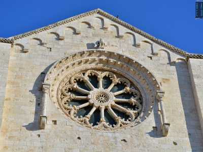 Al centro si inserisce il particolare rosone a doppia raggiera, posto tra due colonnine dai capitelli a motivi vegetali su cui si imposta un arco a tutto sesto finemente scolpito con foglie e fiori